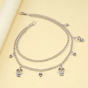 Detail of punk silver double-layer waist chain featuring metallic skull charms and lobster clasps