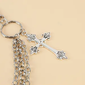 Macro shot of silver punk cross pendant with fleur-de-lis edges and center crystal detail
