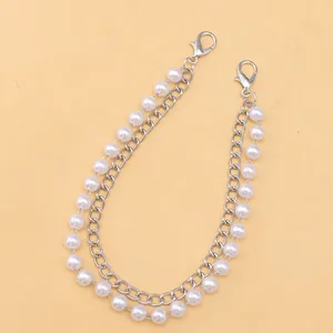 Detail of double-layer bag strap with silver metal chain and white faux pearls