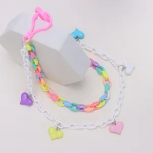 Macro detail of candy-colored acrylic heart flower pendants on double-layered chain