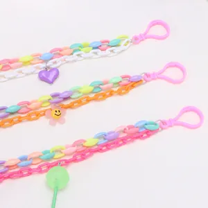 Detail of candy-colored acrylic heart, flower, and lollipop pendants on layered chain