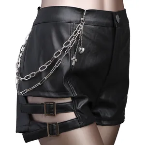 Detail of high-waist black leather shorts with metal chains and cross pendants