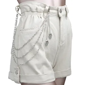 Dettaglio catene punk hip-hop con ciondoli a teschio su pantaloncini di jeans beige