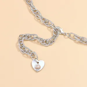 Detail of silver heart necklace featuring a pearl inlay and a thick curb link chain