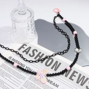 Nahaufnahme einer Y2K-Perlenkette mit rosa Herz- und Blumenanhängern auf Zeitung