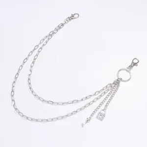 Detailed macro view of punk skull key and rhinestone lock pendants on silver pant chain