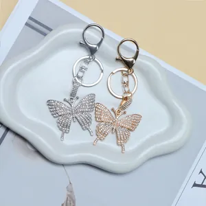 Close-up of gold and silver butterfly keychains with rhinestones on a ceramic tray