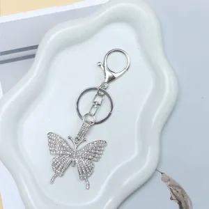 Elegant silver butterfly keychain with sparkling rhinestones on a decorative white dish
