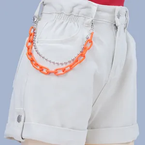 Detail of neon orange acrylic chain and silver ball chain on denim shorts waist
