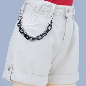 Detail of chunky black acrylic chain and silver bead chain on white denim shorts
