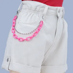 Detail of neon pink acrylic chain and silver bead link on white denim shorts