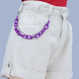 Detail of purple acrylic chain and silver bead chain accessory on denim shorts