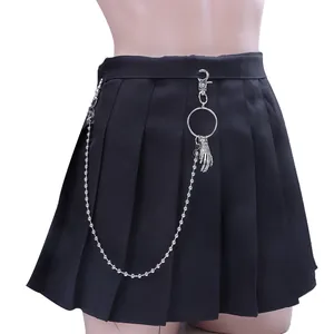 Détail d'une jupe plissée noire avec des chaînes à boules et pendentif main de squelette