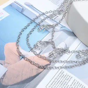 Détail d'une chaîne multicouche en métal argenté avec cinq pendentifs de mains de squelette