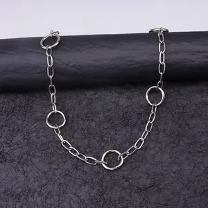 Detail of silver chain belt featuring five large metal rings with a polished finish