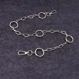 Close-up of silver metal chain belt with geometric rings and lobster clasps on black texture