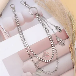 Close-up of gothic silver skull and skeleton hand charms on layered punk metal chains