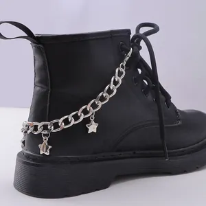 Detalle de dijes de estrellas y cadena de metal plateado en botas de cuero negro
