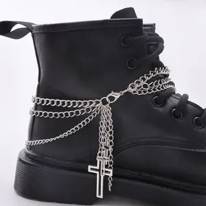 Catene per scarpe multistrato argentate con pendenti a croce su uno stivale nero