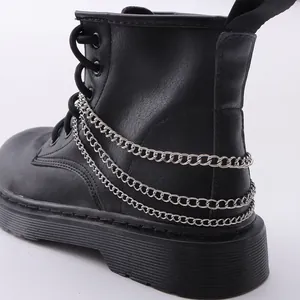 Dettaglio di catene metalliche argentate multistrato su stivali martin punk neri