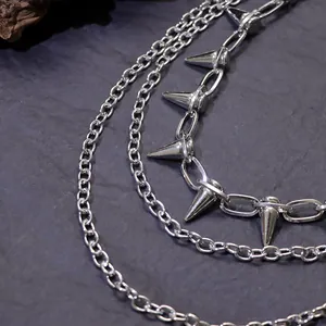 Close-up of punk multi-layer silver metal chain with conical spikes on stone background