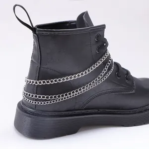 Gros plan de bottines noires mates avec des chaînes métalliques argentées style punk