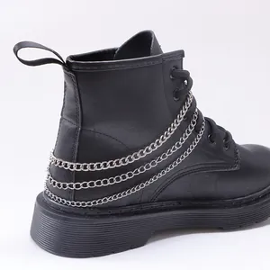 Detalle de cadenas plateadas en botas punk negras con cordones y suela de goma gruesa