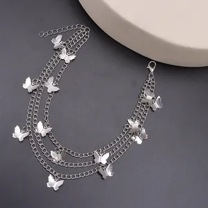 Detailed view of layered butterfly shoe chains with silver metallic pendants and lobster clasp