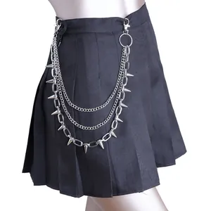 Detalle de cadenas punk plateadas con púas cónicas en una falda de tablas negra