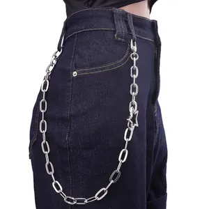 Detail of silver star pendant on thick metal chain draped over blue denim jeans