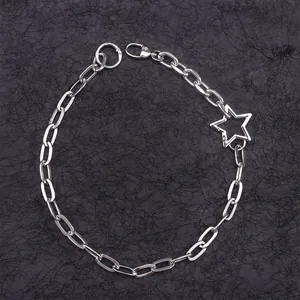 Macro detail of silver metal chain featuring a large hollow star pendant and clasp