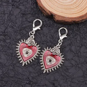 Close-up of gothic red heart shoe charms with metal rose and evil eye on black background