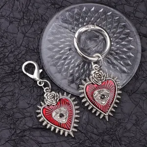 Gothic silver heart shoe charms with red evil eye and rose detail on dark background