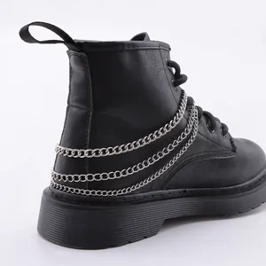 Nahaufnahme matter schwarzer Lederstiefel mit dreifacher silberner Metallkette an der Ferse