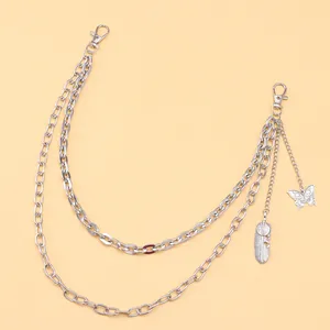 Detail of silver layering chain with butterfly and feather charms for trousers