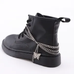 Detaillierte Makroansicht der silbernen Ketten und Schmetterlingsanhänger an schwarzen Boots