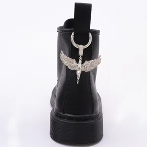 Close-up of gothic silver angel wing charm on black leather boot with rhinestone detail