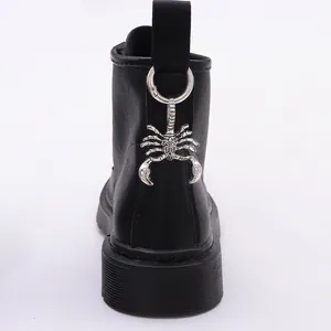 Close-up of metal scorpion pendant hanging on the heel of black punk style boots
