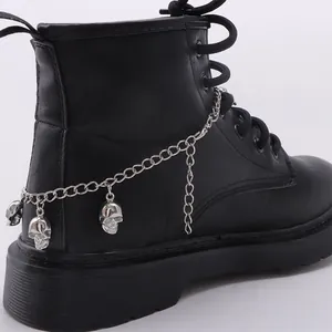 Detail of silver skull pendants and metal chains on a black punk platform boot