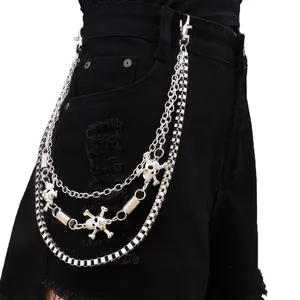 Detalle de cadena de pantalón triple plateada con calavera y estampado de tablero de ajedrez