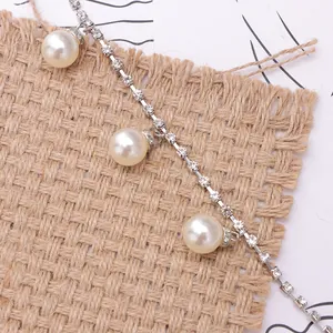 Detail of silver chain with sparkling rhinestones and elegant white pearls for shoes