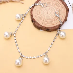 Sparkling rhinestone shoe chain with pearl pendants and lobster clasps on wooden display