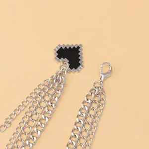 Close-up of a silver-tone multi-layer shoe chain with black mosaic pixel heart pendant