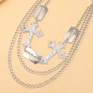 Close-up of layered silver metal necklace with hollow cross and razor blade pendants