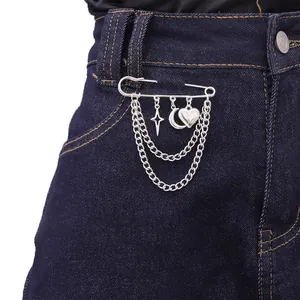 Silver lock brooch with star, moon, heart charms and layered chains on denim jeans