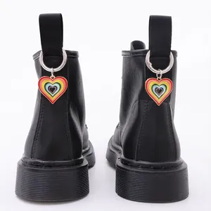 Detalle de los colgantes de corazón arcoíris en las presillas traseras de botas de cuero negro