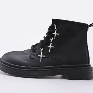 Detalle de botas militares negras mate con colgantes de espada gótica plateada en ojales