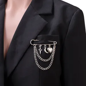 Detailed view of silver safety pin brooch with hanging chains and star moon charms