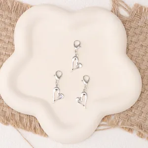 Close-up of three polished silver heart pendants with lobster clasps for shoe charms