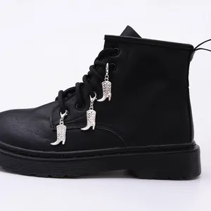 Close-up of silver metal boot charms with scroll relief on black lace-up Martin boots